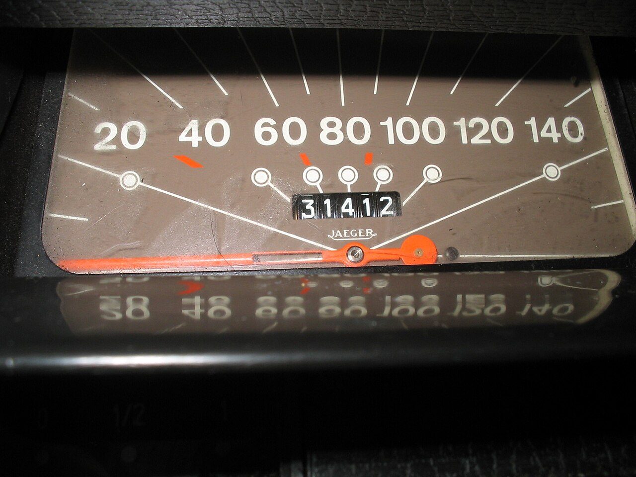 A car speedometer with a mechanical odometer below the scale, its white-on-black number wheels reading 31412