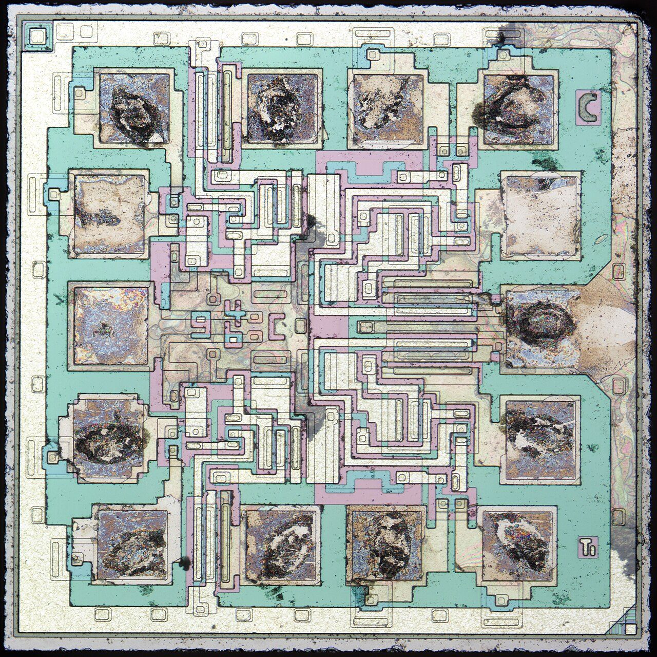Microscope photograph of the SN5400 die: a square of silicon with fourteen bonding pads round the edge and four identical clusters of circuitry between them